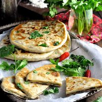 Aloo Paratha (Indian Potato Stuffed Flatbreads) filled with mashed potato and spiced beef on a tray, ready to be served.