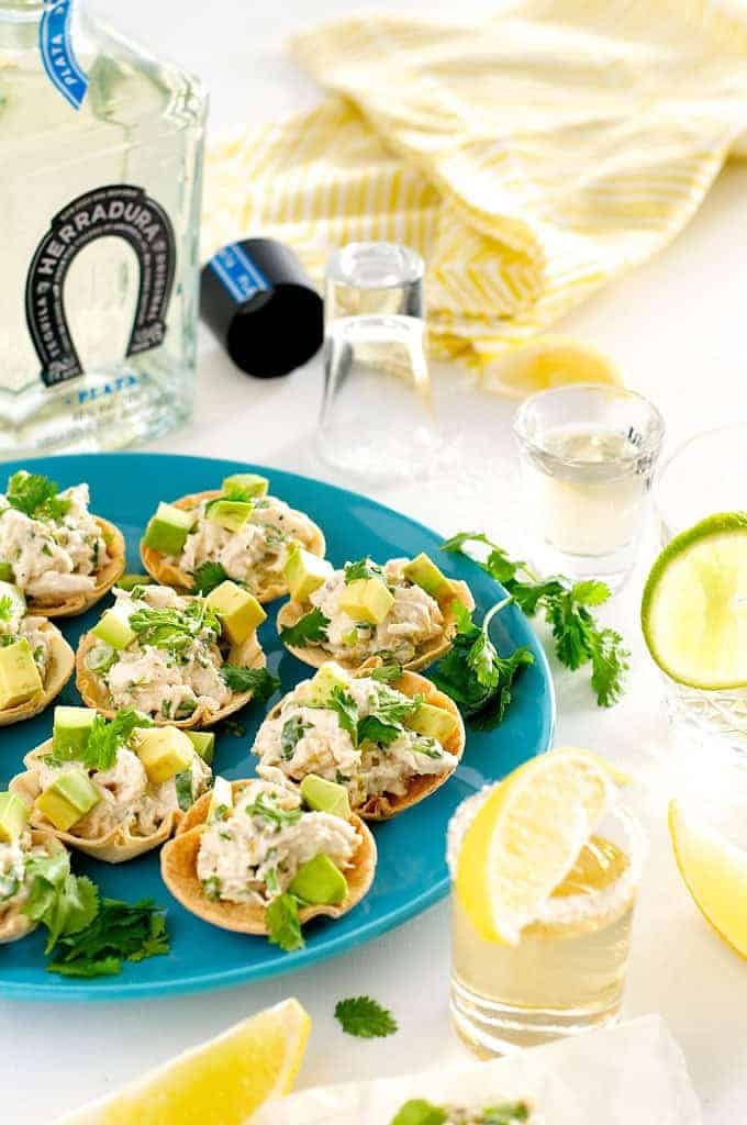 Table setting photo of Spicy Little Muffin Tin Chicken Tostadas with tequila bottle and glass
