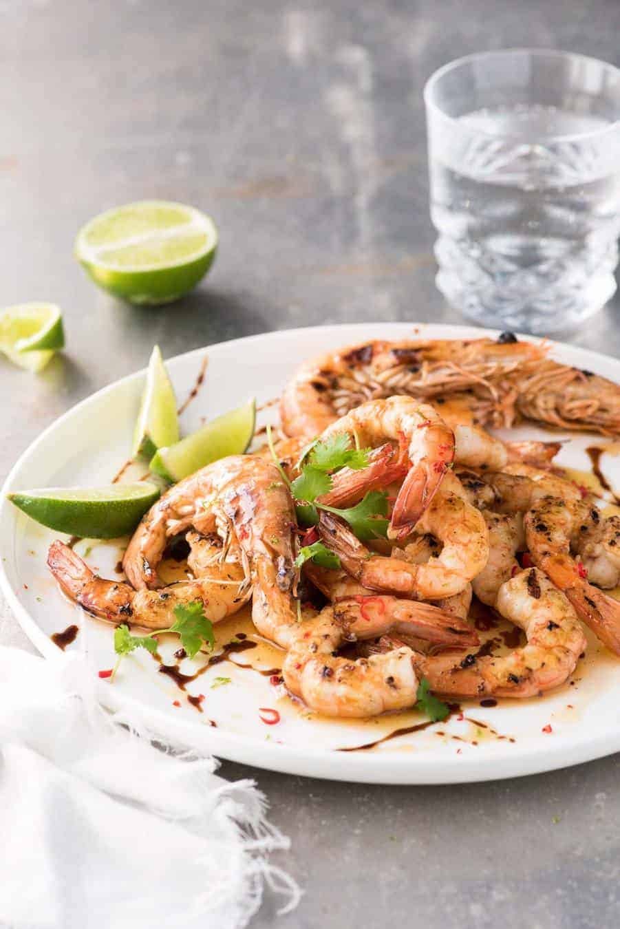 Asian Grilled Shrimp / Prawns on a white plate, drizzled with brown butter, lime and sweet soy, ready to be served.