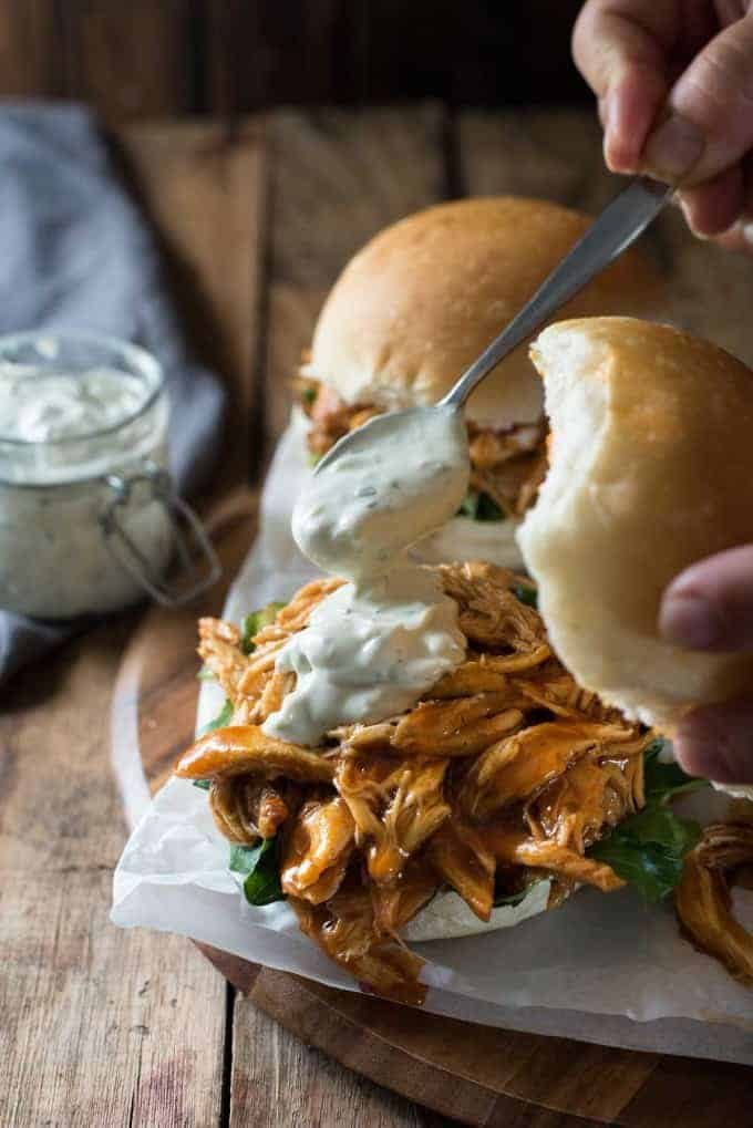 Spooning blue cheese sauce into Honey Buffalo Chicken Sliders