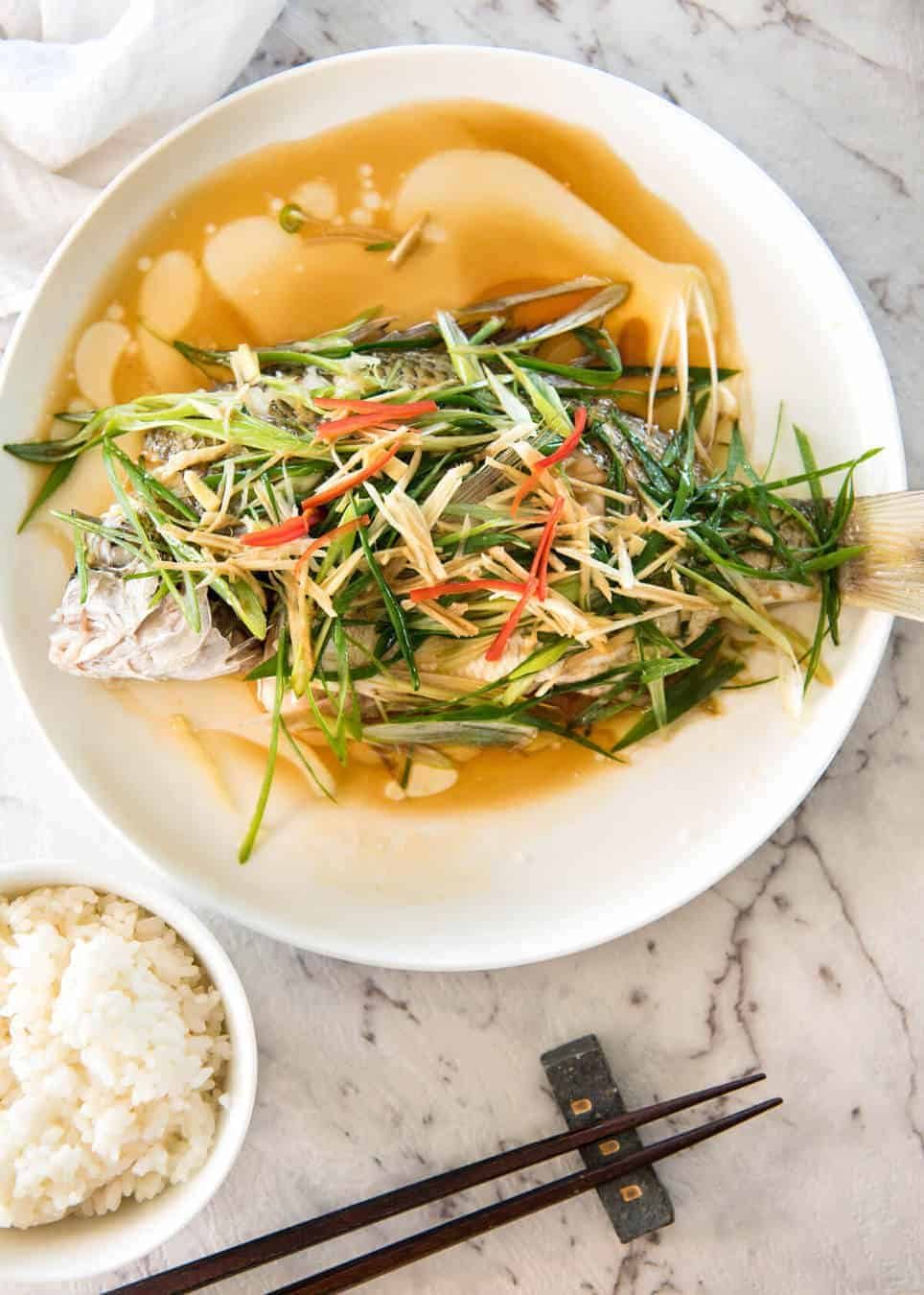 A Chinese Steamed Fish topped with Ginger and Shallots and seasonings, with hot oil poured over it to create a dramatic sizzle and an amazing sauce. So simple, yet so utterly delicious. Steam OR bake the fish! www.recipetineats.com