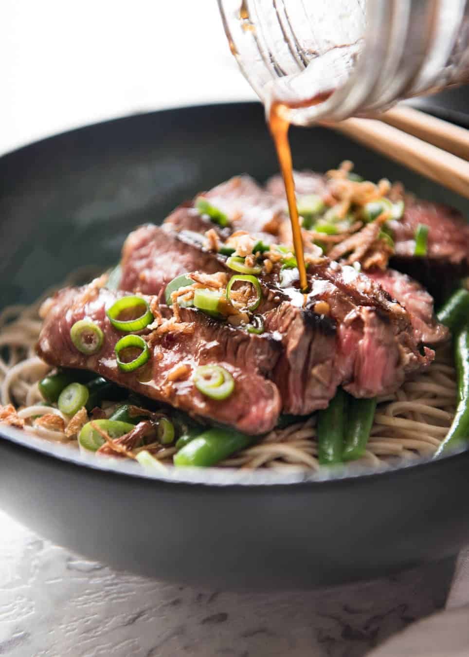 Sauce being poured over Beef Soba Noodle Bowls
