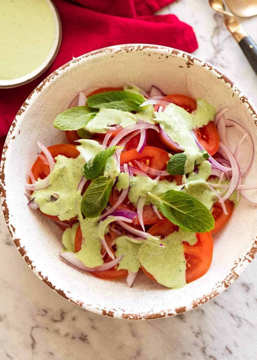Indian Tomato Salad drizzled with Mint Dressing in a rustic cream bowl, ready to be served