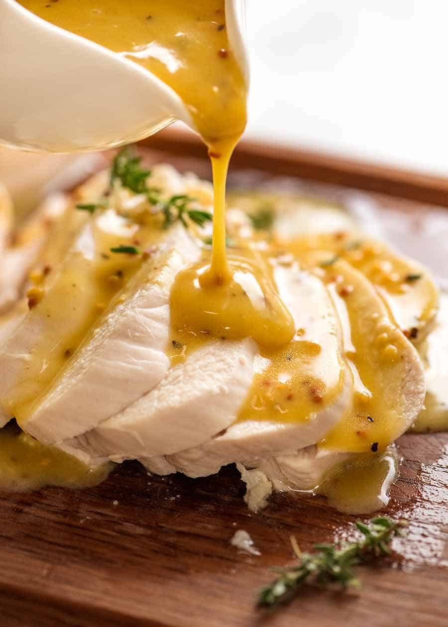Pouring honey mustard sauce over perfectly poached chicken