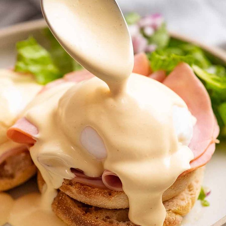 Pouring Hollandaise Sauce over Eggs Benedict